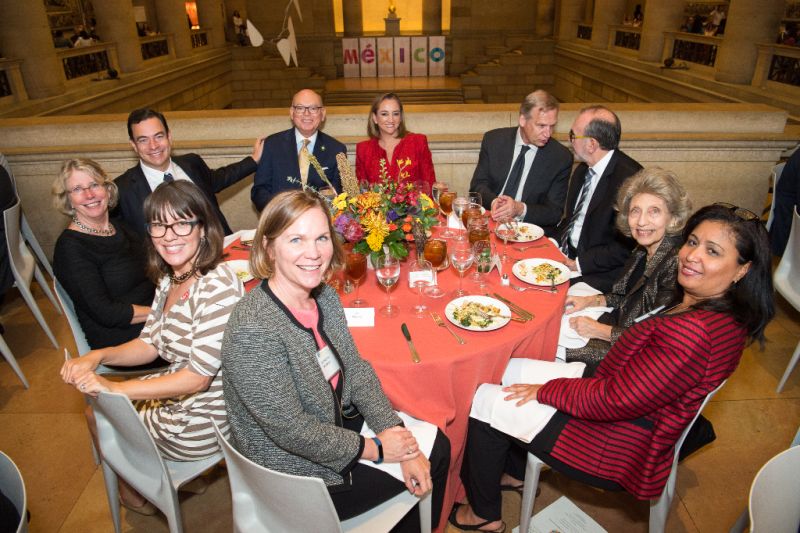 Round dinner table with attendees smiling during Annual Members Meeting 2016 banquet.